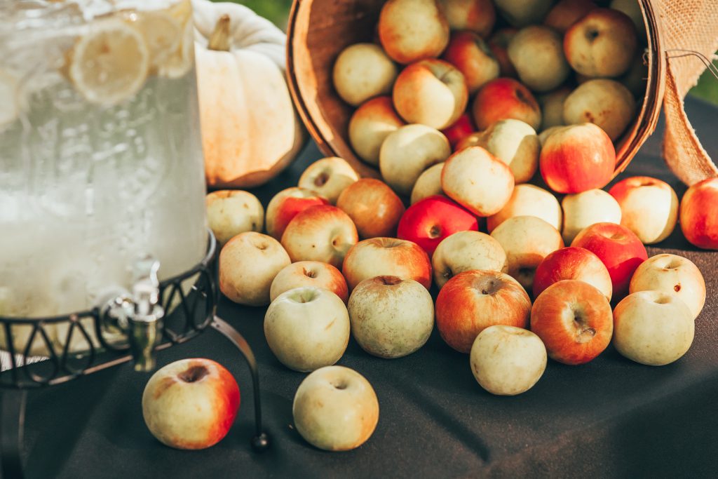 drink station with water pitcher and barrel of red and yellow colored apples