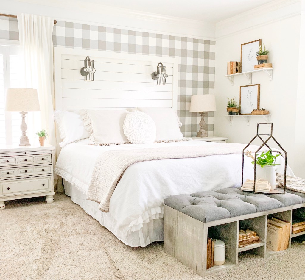 bedroom with large bed and bench and shelf decor of botanical prints