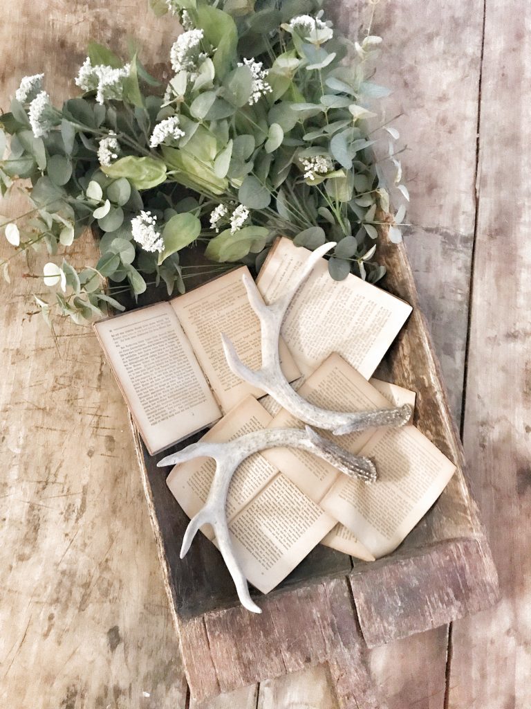 vintage books displayed in a wooden bowl with greenery